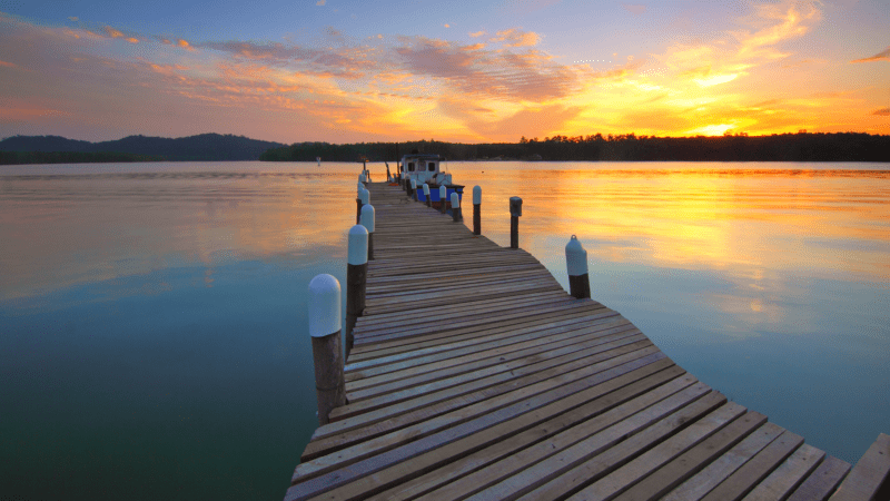 A pier stretches into the water toward a stunning sunset.